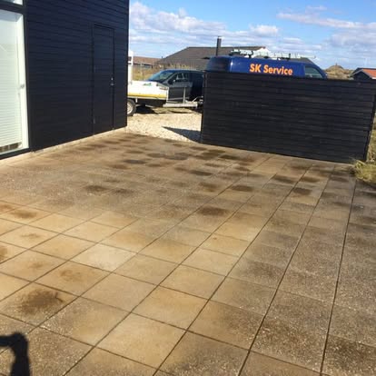 Fliseterrasse ved sommerhus med mørke pletter og alger før afrensning